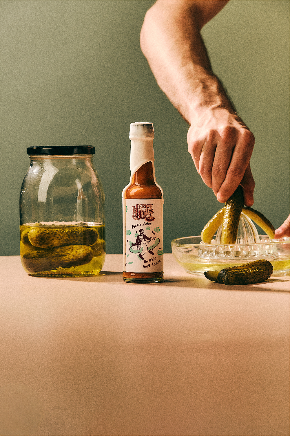 Pickle Juice Buffalo Hott Sauce with Ingredients and Pickles being Juiced and Jar of Pickles - Heriot Hott